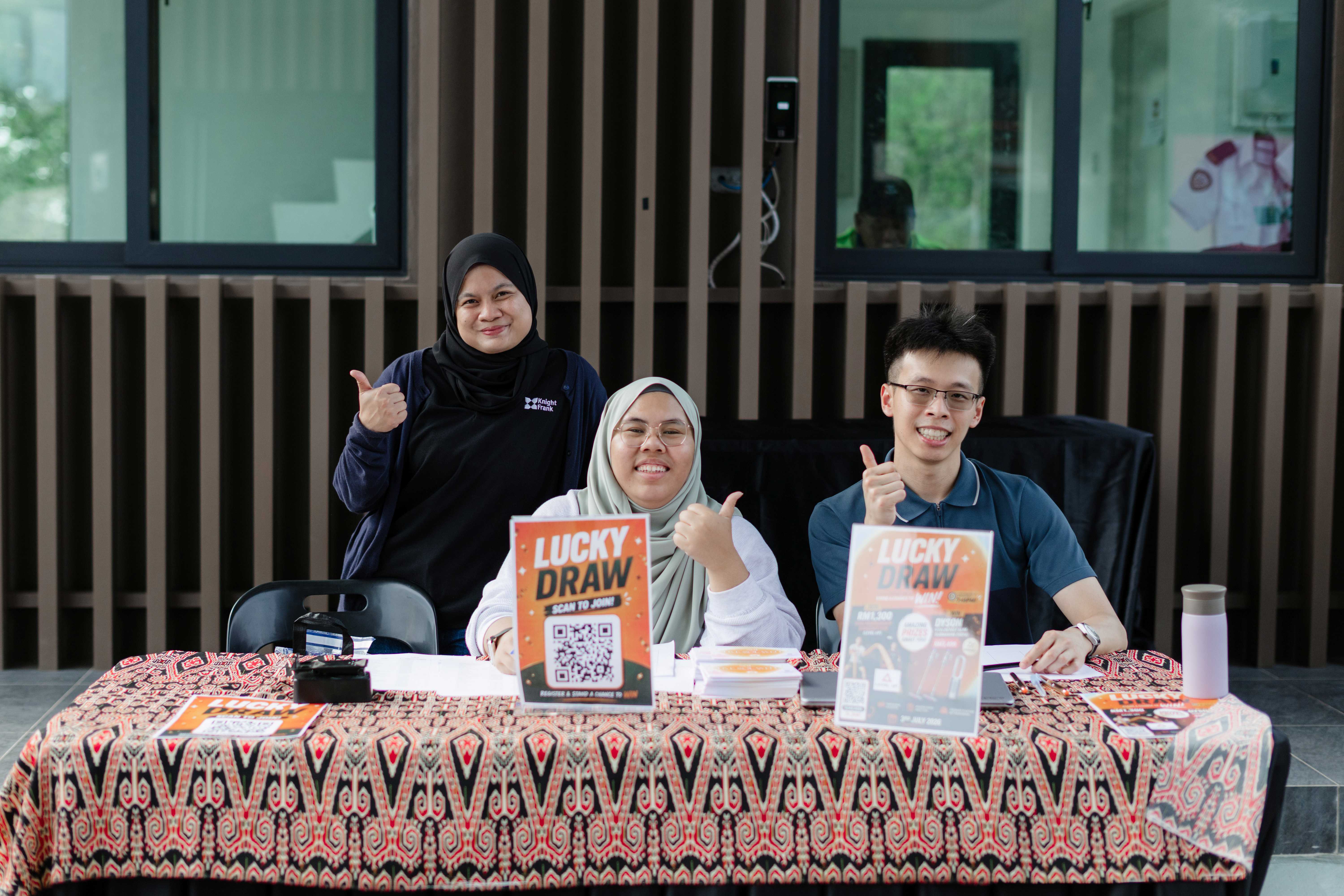 Three EXAL team members welcoming visitors at a community event booth